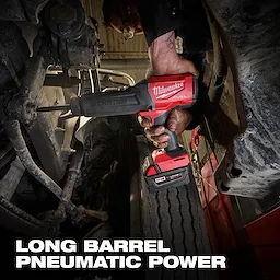 Hand holding an M18 FUEL STRIKER Hammer Chisel between vehicle parts above a large tire.