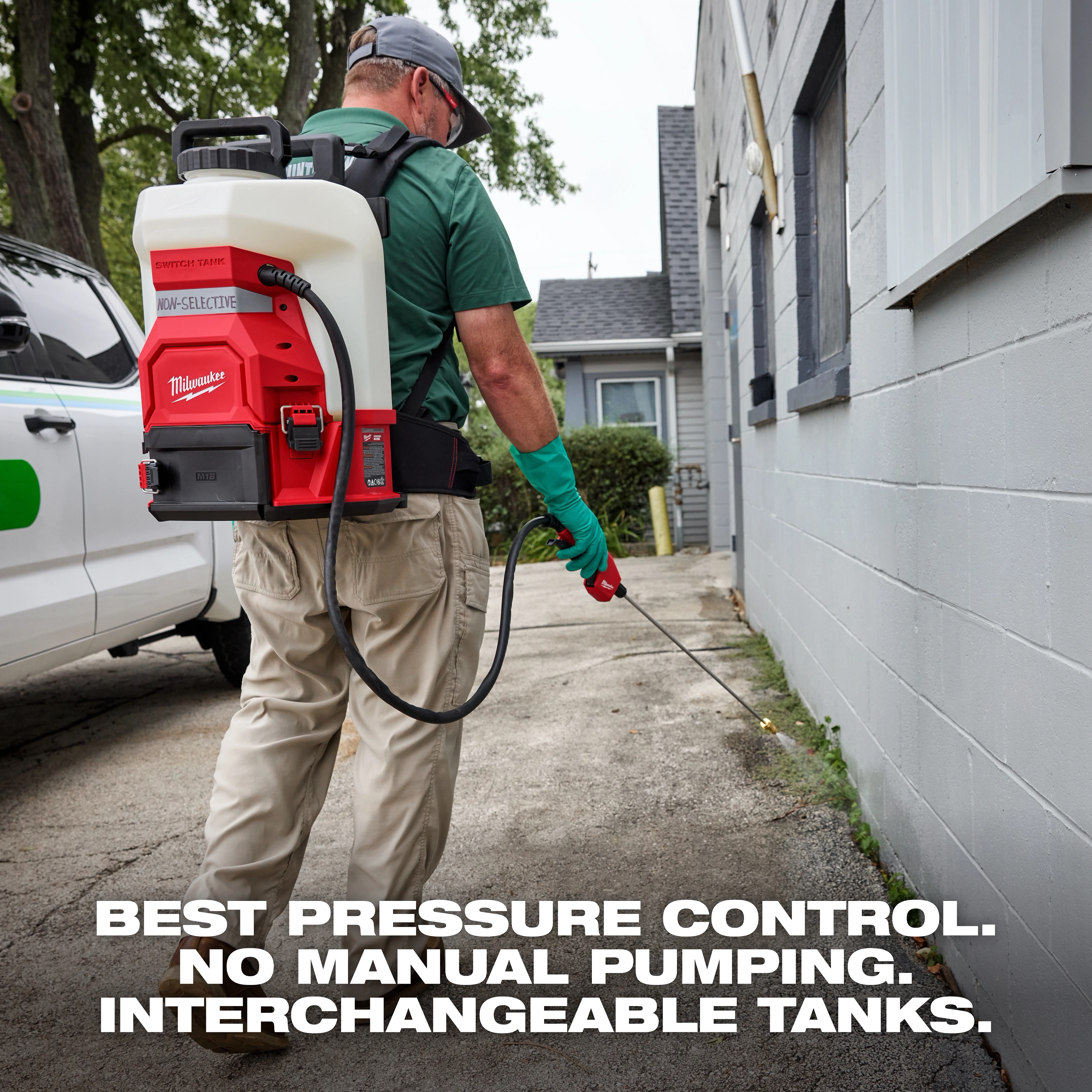 A person in outdoor workwear uses a Milwaukee backpack sprayer along the side of a building. The sprayer features "best pressure control," requires "no manual pumping," and has "interchangeable tanks," as stated in bold text at the bottom of the image.
