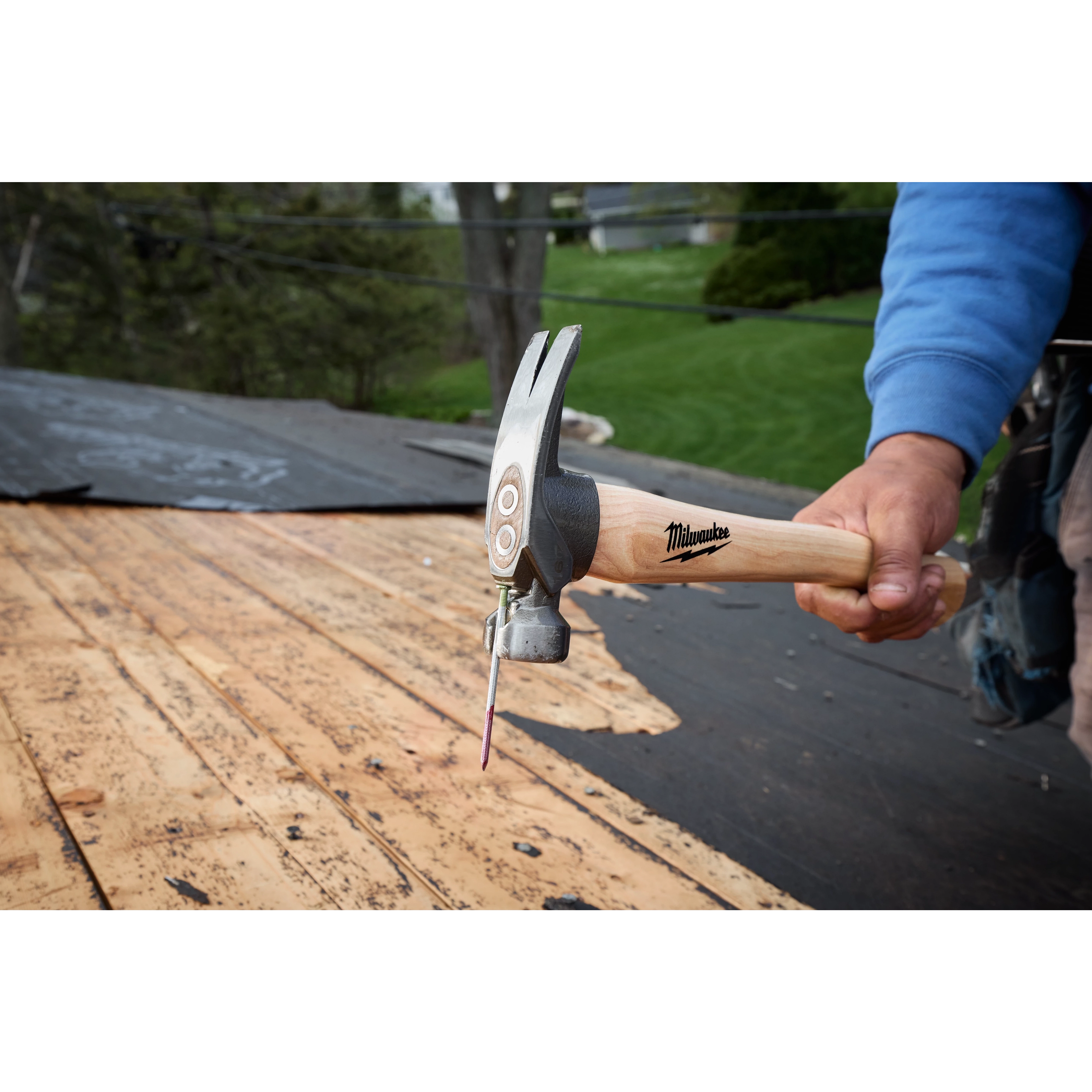 16oz Smooth Face Hickory Handle Hammer driving a nail into roof decking outdoors.
