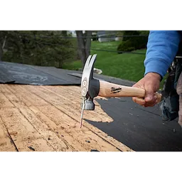 16oz Smooth Face Hickory Handle Hammer driving a nail into roof decking outdoors.
