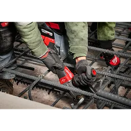 Two construction workers are using the M18 FUEL™ #10 (1-1/4") Rebar Cutter to cut steel rebar. The rebar cutter is red and black, and the workers are wearing gloves and protective clothing while working on a concrete rebar structure.