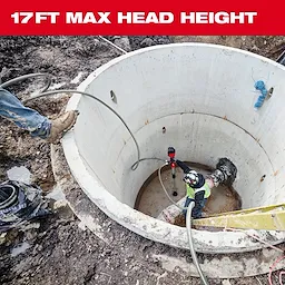 A construction worker is using the M18™ Brushless Stick Transfer Pump in a large, cylindrical concrete pit. The image highlights a "17 FT MAX HEAD HEIGHT" in bold red text at the top. Another worker stands at the edge of the pit. The area is muddy.