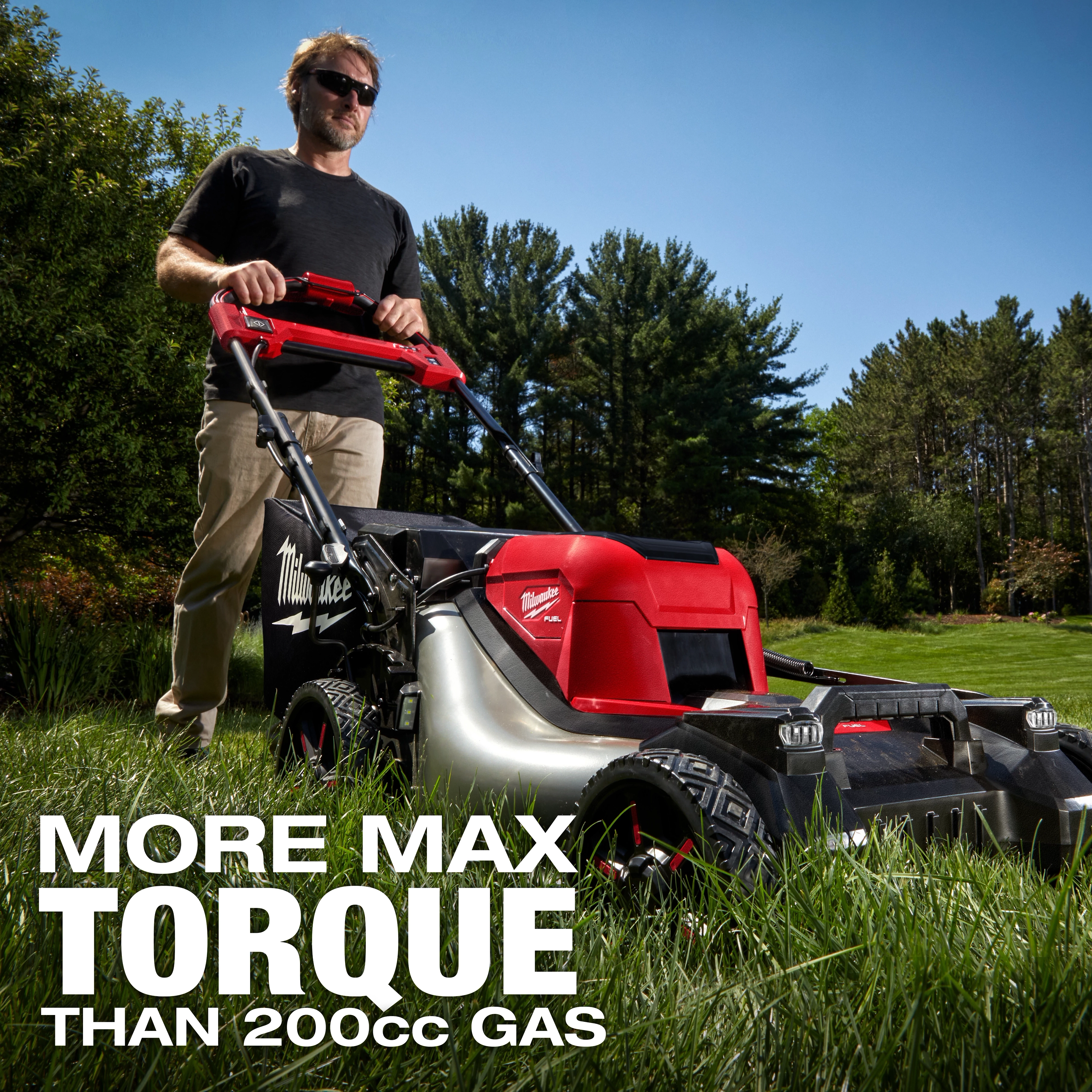 A person uses the M18 FUEL™ 21" Self-Propelled Dual Battery Mower on a grassy lawn with trees in the background. The text on the image reads "MORE MAX TORQUE THAN 200cc GAS".