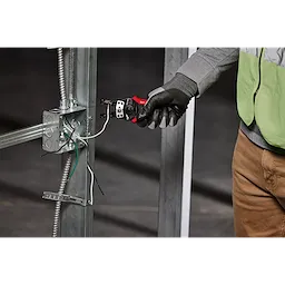 A person wearing gloves uses an Automatic Wire Stripper & Cutter to strip wires connected to a metal electrical box framework.